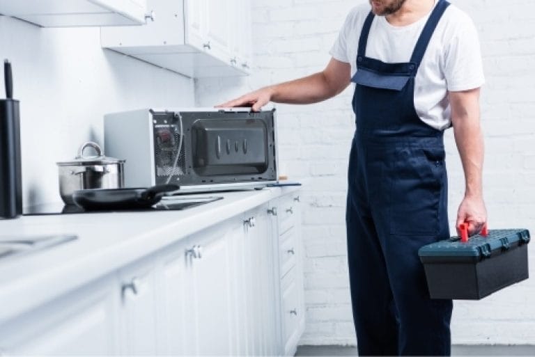 Technician repairing a microwave oven in a residential kitchen