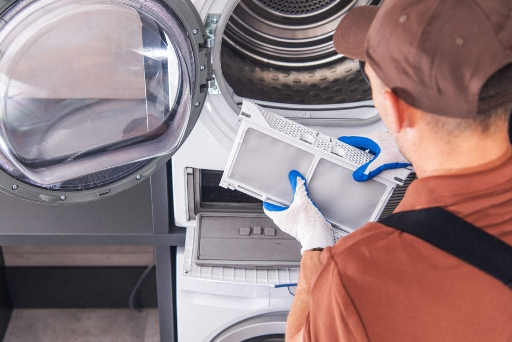 Technician cleaning the lint filter of a tumble dryer during servicing